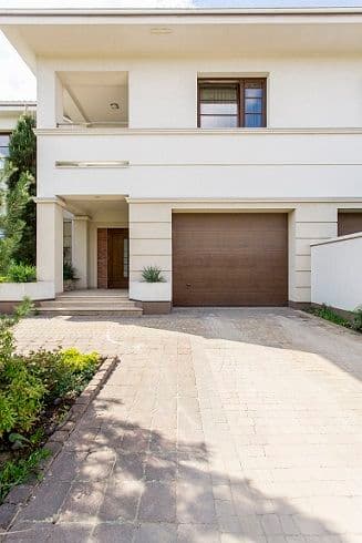 Modern two-story house with a brown garage door and landscaped driveway.